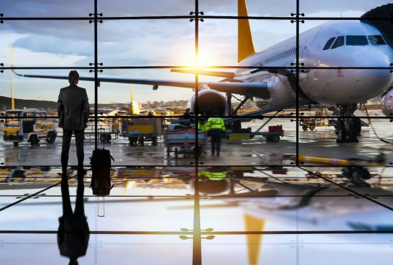 travelling buisness man looking at the aeroplane on the tarmac at sun set